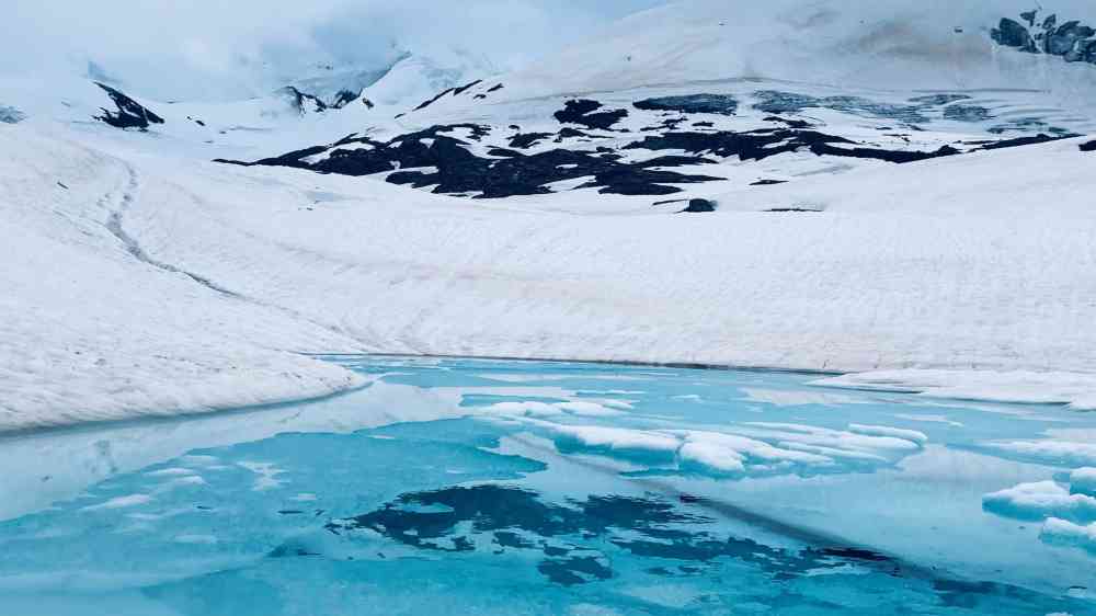 Stunning view of a glacier with blue icy water under a cloudy sky.