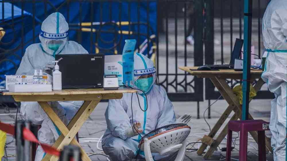 Medical professionals in protective gear conducting outdoor testing operation.