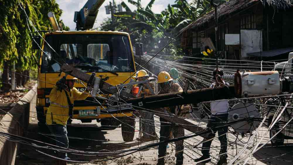 Utility workers repairing fallen power lines in a city street, highlighting teamwork and infrastructure maintenance.