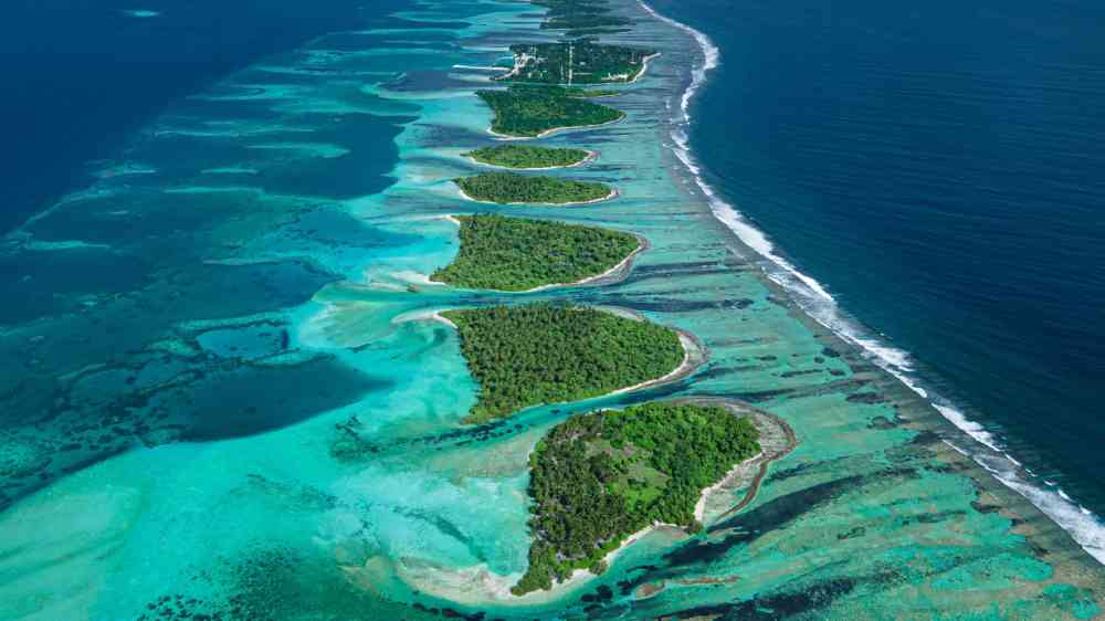 A breathtaking aerial shot of a Maldives atoll with vibrant blue waters and green islands.