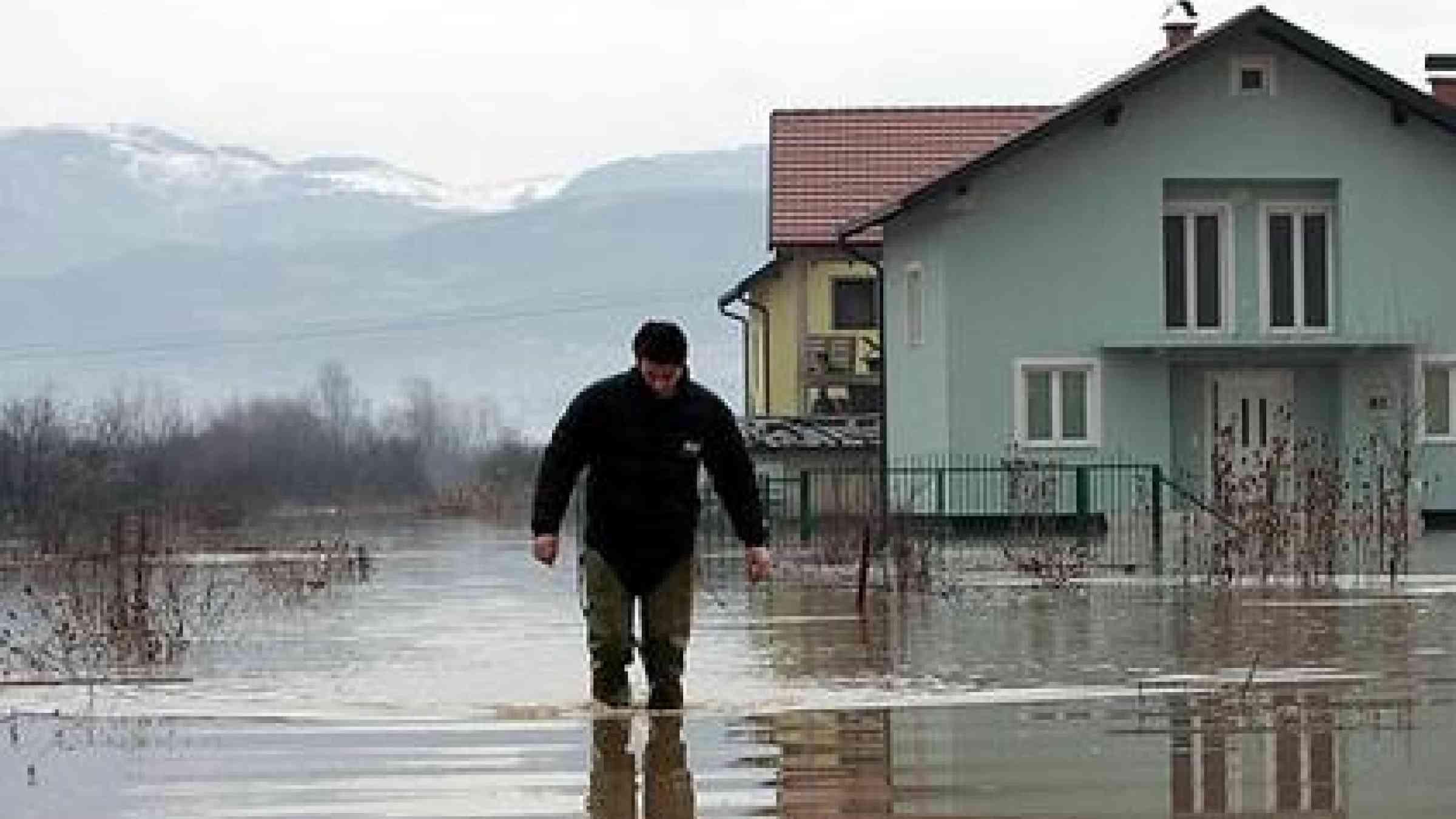 A Bosnian man walks through flooded water near Sarajevo. Heavy rain and melting snow from mountains caused flooding of the river Bosnia in a suburban part of Sarajevo leaving more than 30 houses flooded in January 2010.