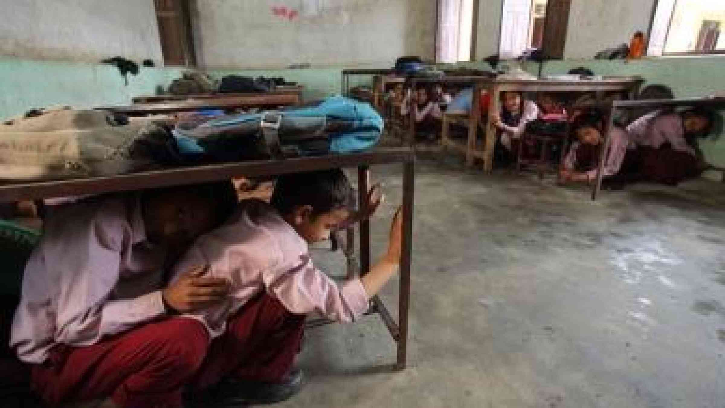 Photo by Jim Holmes for AusAID Students in Matatirtha, Nepal, which is in the process of being redeveloped to make the school more earthquake proof. As part of this process children are taught how to take shelter beneath their desks in case of an earthquake