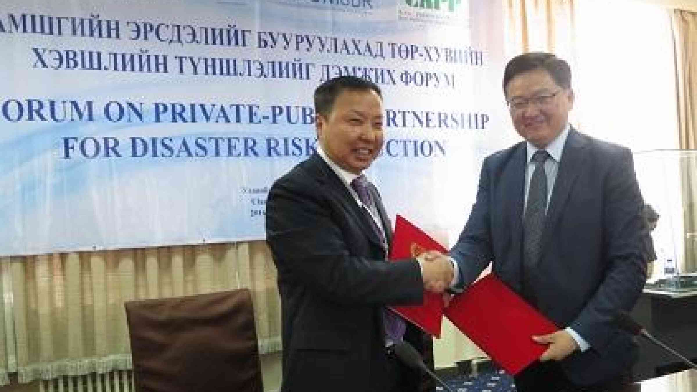 The Deputy Chief of the National Emergency Management Agency, Colonel Gombojav Ariunbuyan (left), and the President of the Mongolian National Chamber of Commerce and Industry, Mr Baatarjav Lkhagvajav, exchange copies of the agreement between the two sides. (Photo: UNISDR)