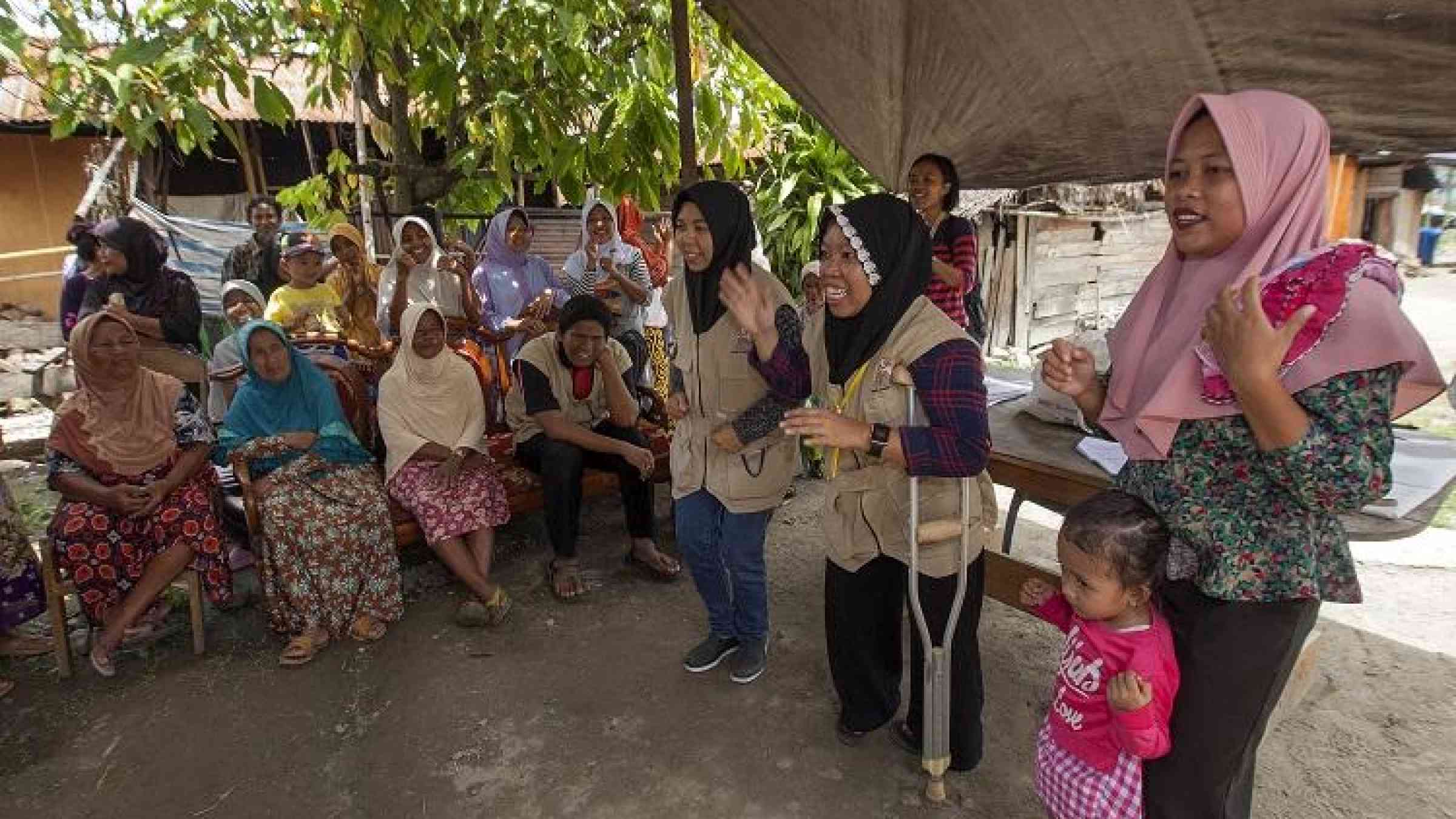 (c)Dwi Oblo/ASB Indonesia and the Philippines. Two members of a Disabled People's Organisation (DPO), wearing khaki vests, are delivering a hygiene promotion session for community members of Mantikole Village, Sigi, Central Sulawesi, Indonesia