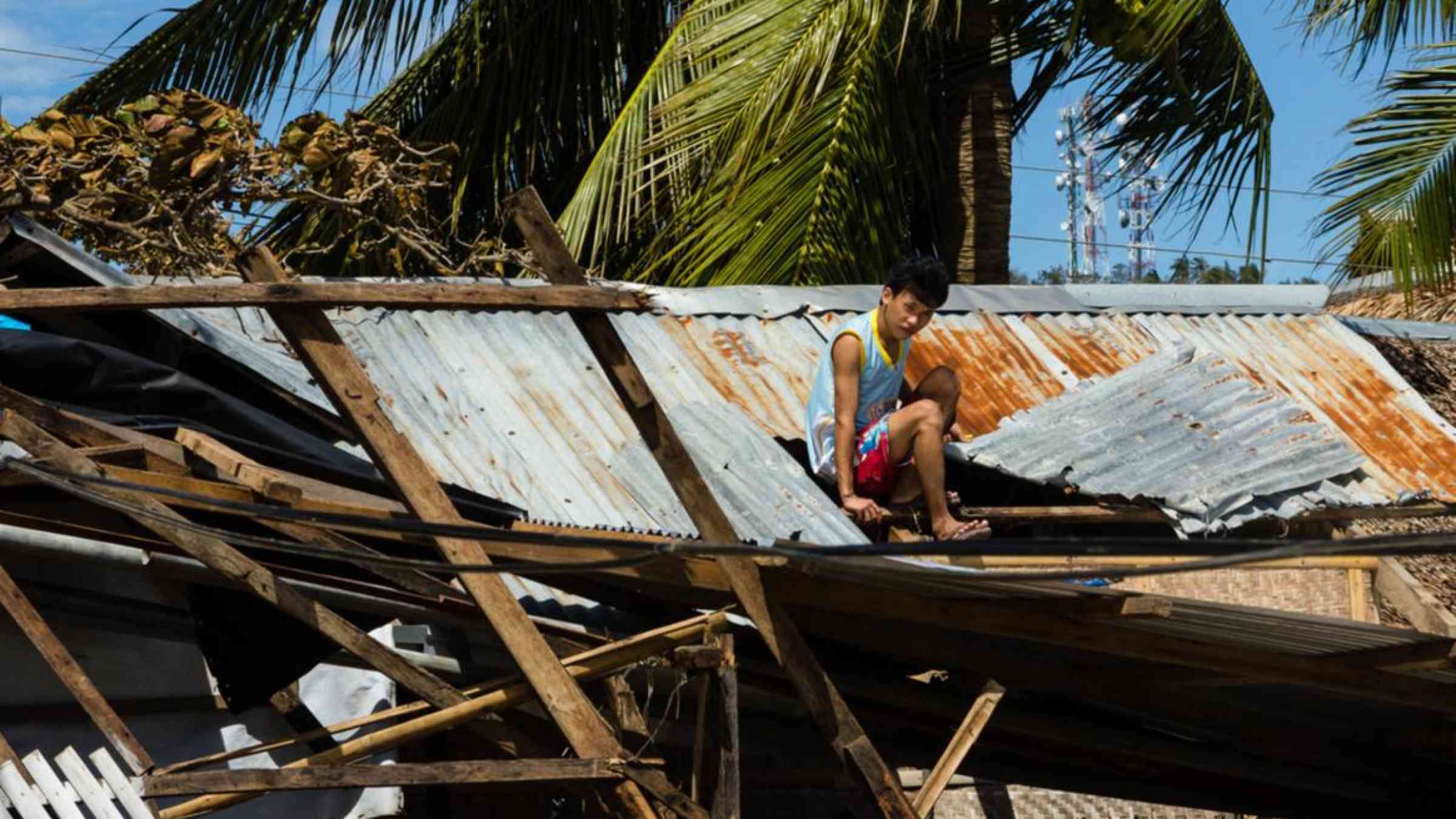 A Filippino man repairs a roof destroyed by Typhoon Haiyan, 2013. Richard Whitcombe/Shutterstock