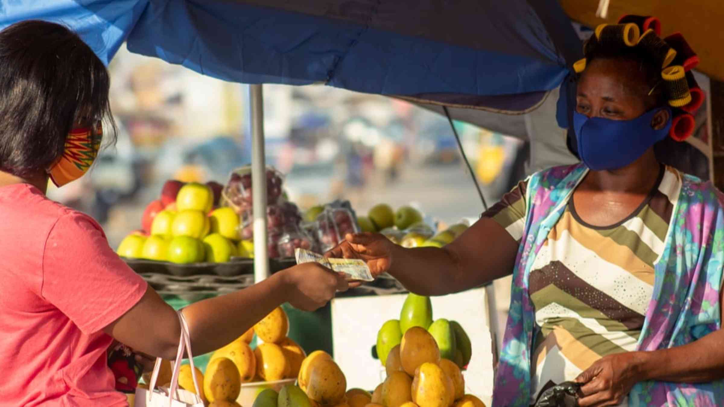 Two women in Africa wearing a mask in a local market