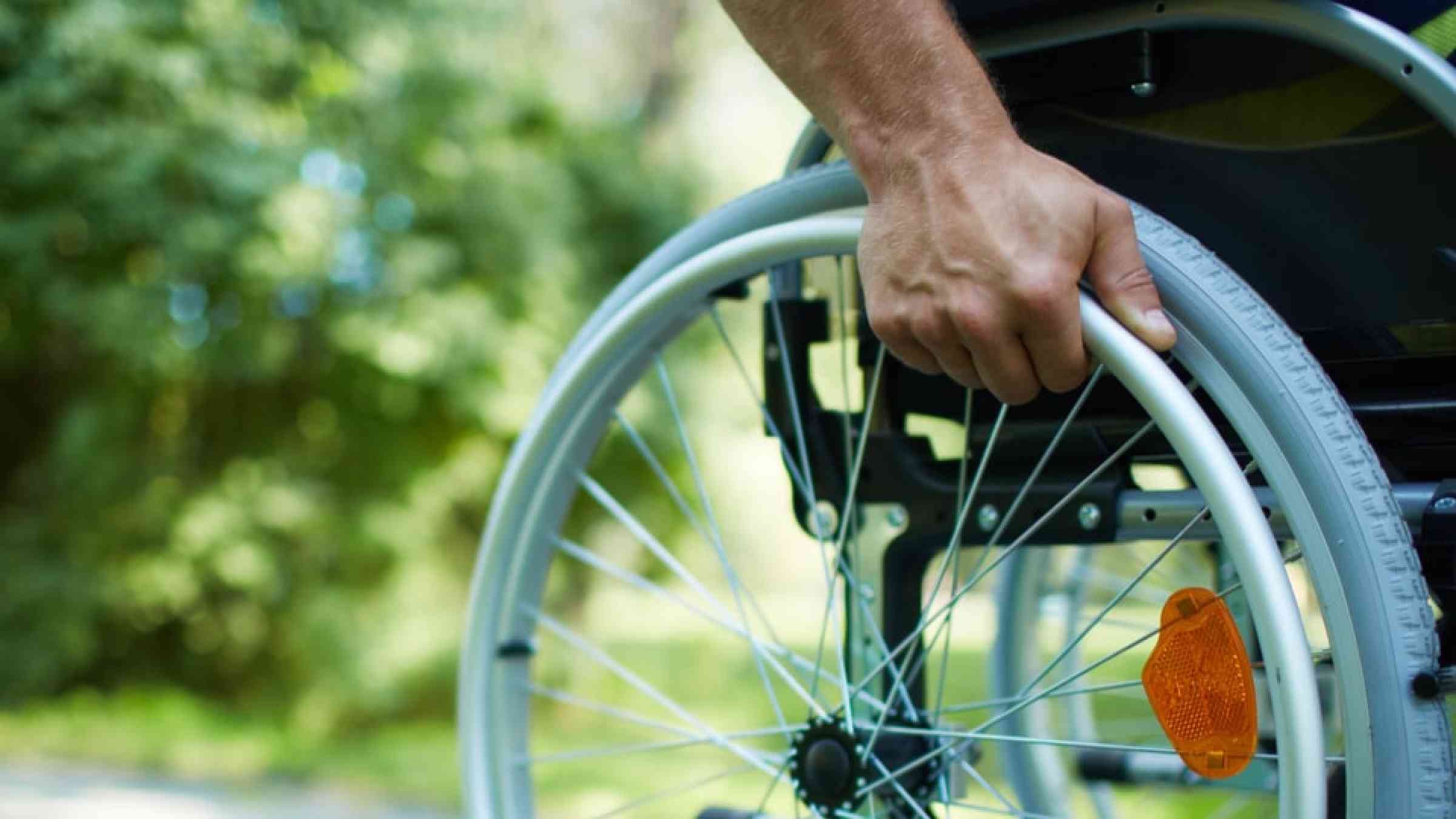 Hand holding the wheel of a wheel chair