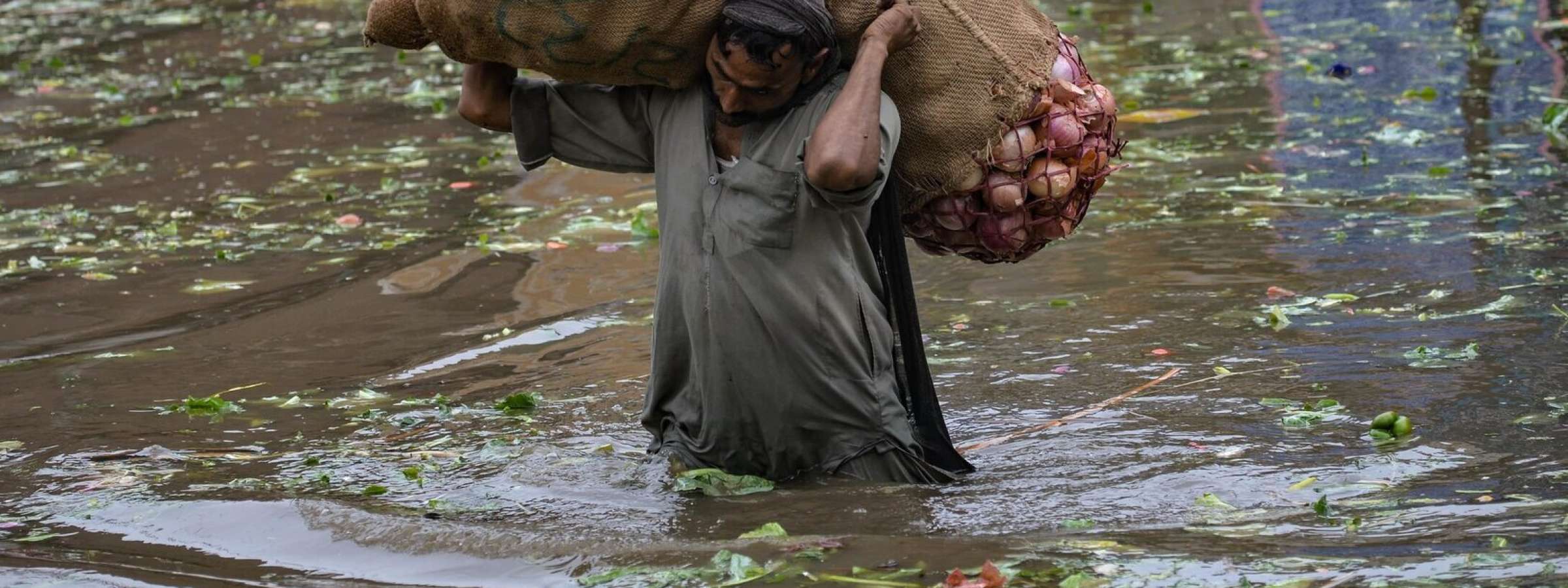 A laborer carries a sack of onions above floodwaters in Lahore, Pakistan