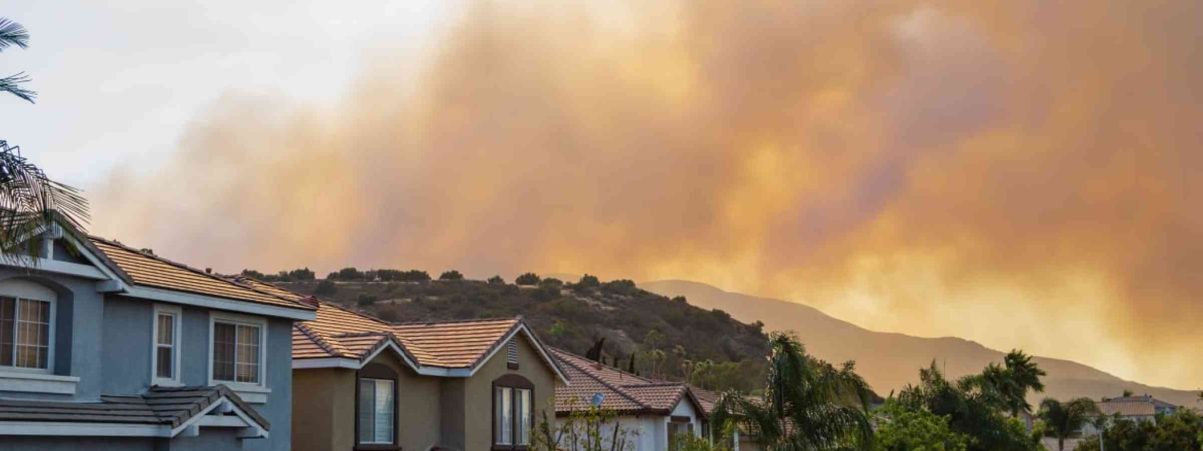 Houses with wildfire smoke in the background
