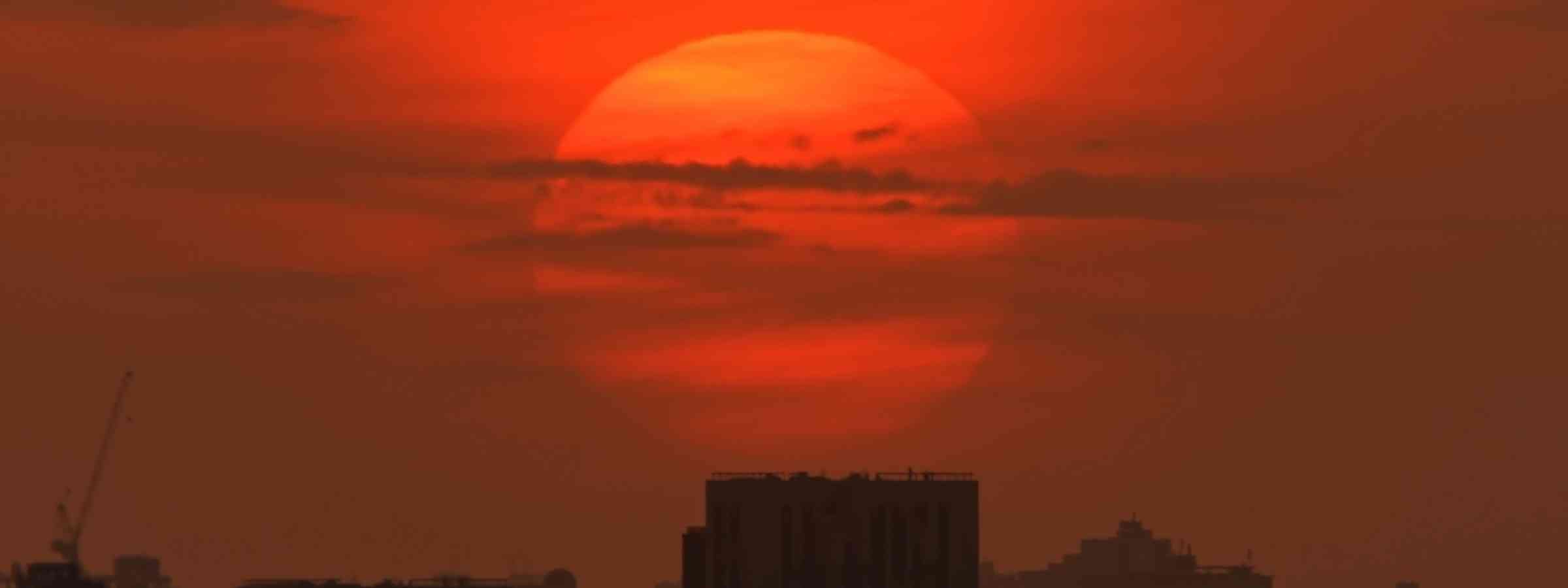 Heat city City skyline hot sunset, downtown cityscape lit with large warm sun disk sun set light.