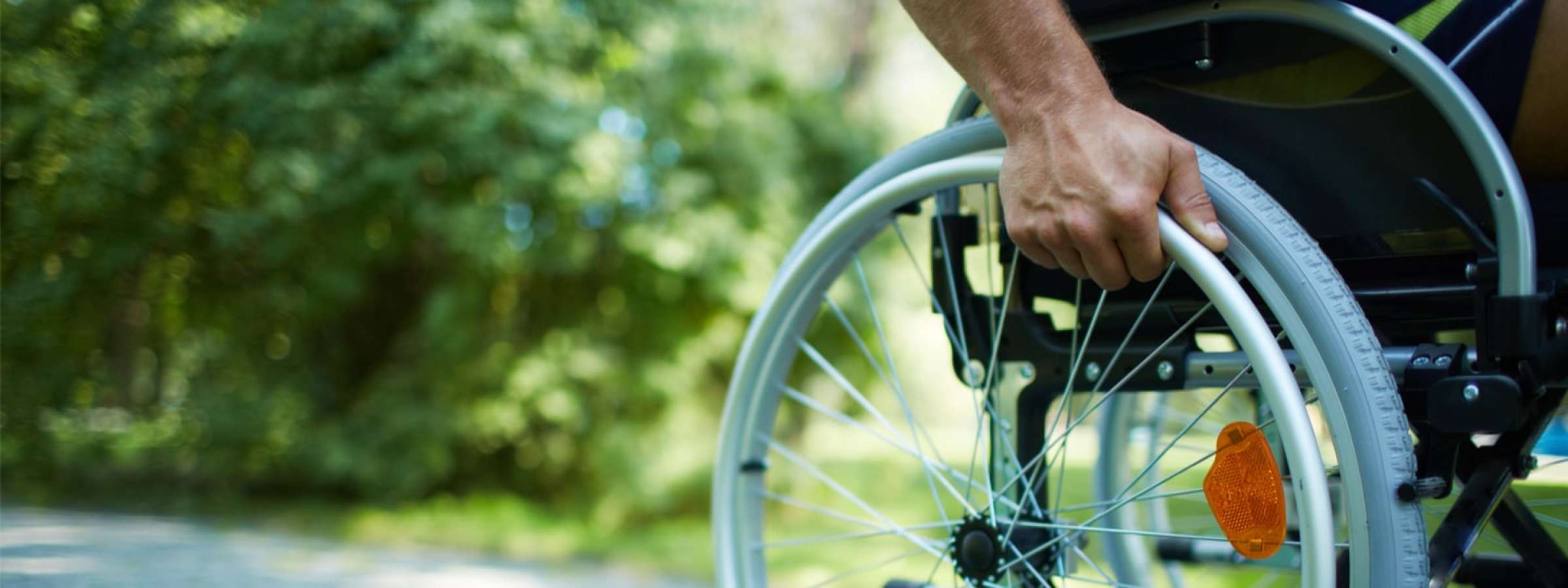 Hand holding the wheel of a wheel chair